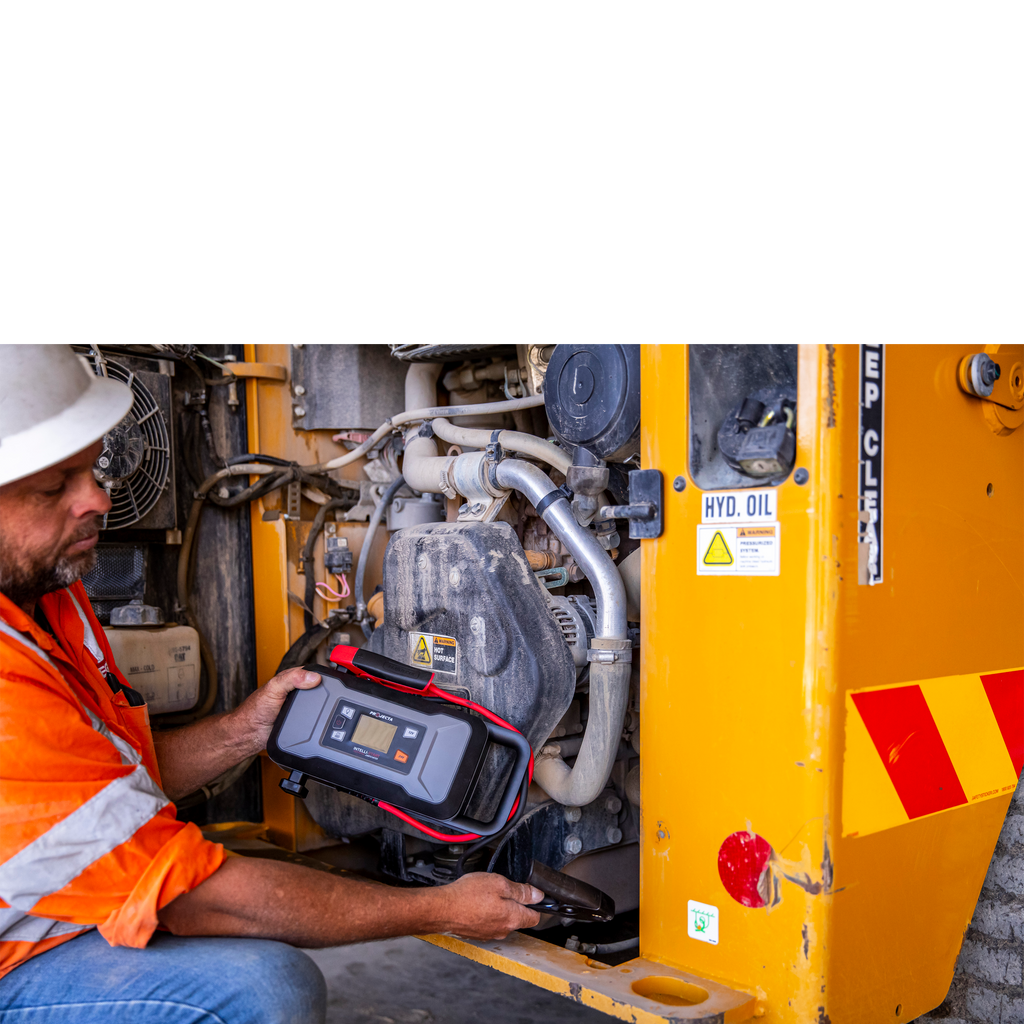 Person using a diagnostic tool on a yellow industrial machine